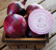 Front view of Red Spring onion bulbs, one sliced to show wine-red interior rings, arranged in a wooden basket