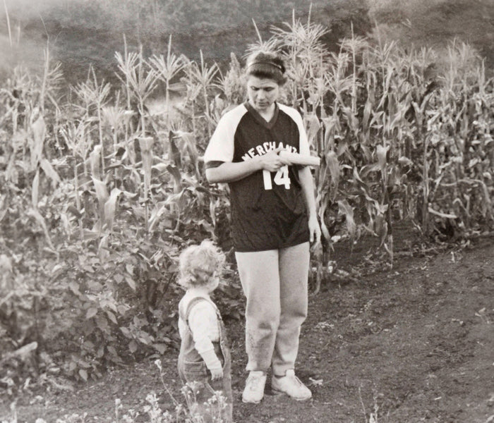 Black and white photo of a person and child standing in a cornfield
