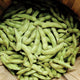 Close-up of Midori Giant edamame pods showing fuzzy green pods piled in a wooden crate
