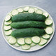 Overhead view of Sweet-Slice cucumbers on a plate showing glossy dark green skin and sliced rounds with white interior