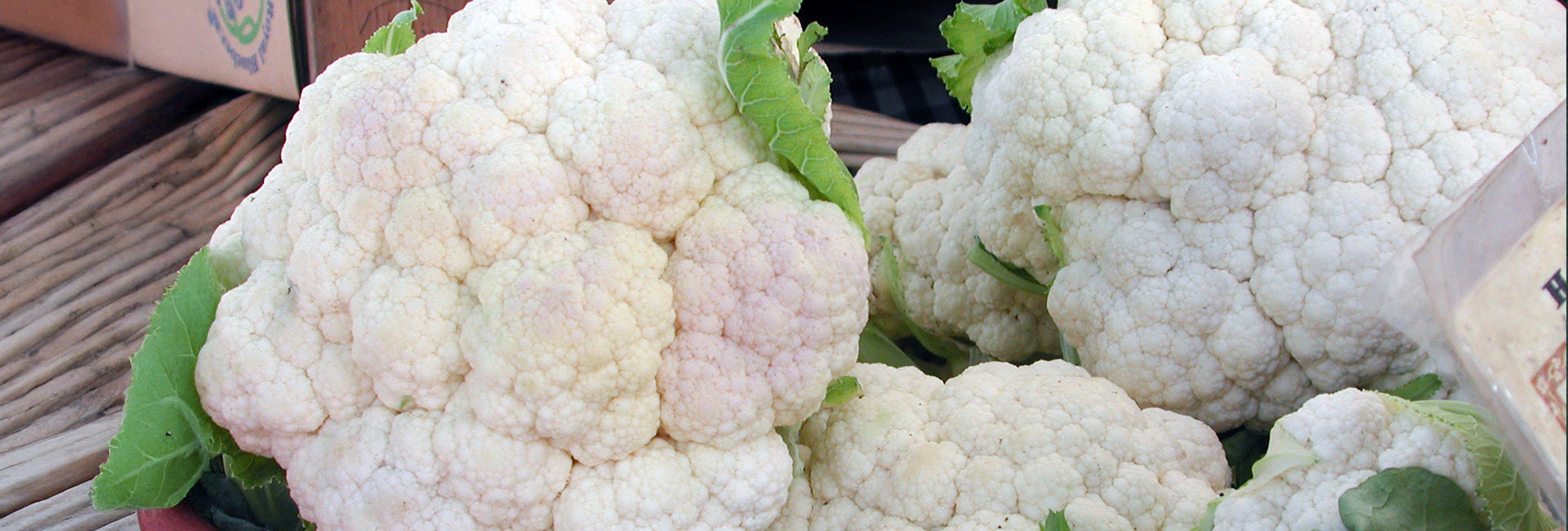 Close-up of cauliflower with green leaves on a wooden surface