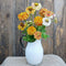 Close-up of Peppermint Stick zinnia blooms showing red-striped cream, white, yellow and orange petals in white vase