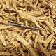 Close-up of dried American ginseng root pieces showcasing thin tan root shreds on a light background