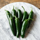 Close-up of Black Magic jalapeño peppers showing deep inky green color and thick walls on a light background