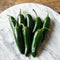 Close-up of Black Magic jalapeño peppers showing deep inky green color and thick walls on a light background