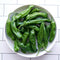 Top-down view of Mellow Star shishito peppers showing wrinkled green 3–4 inch pods in a white bowl on a tiled background