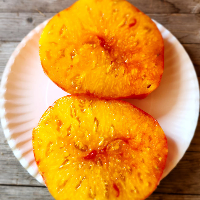 Close-up of Ginfiz tomato showcasing orange-striped skin and sliced interior on white background