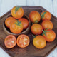 Close-up of Jaune Flamme tomato fruits showing deep orange color and sliced interiors in a wooden bowl