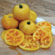 Close-up of Golden Treasure tomato showing whole and sliced golden-yellow fruits with marbled interior on a light wooden surface
