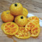 Close-up of Golden Treasure tomato showing whole and sliced golden-yellow fruits with marbled interior on a light wooden surface