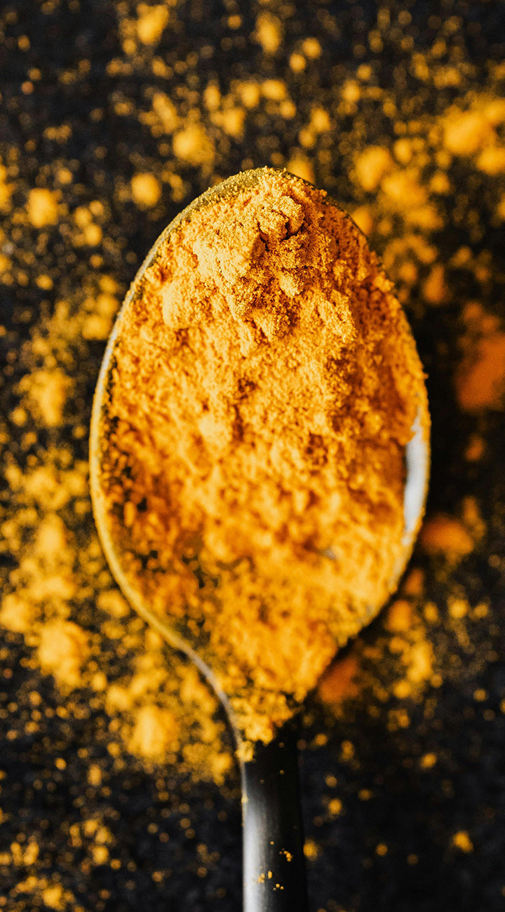 Spoon filled with turmeric powder on a dark background