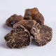 Several hazelnut truffles displayed on a white background, showing their rugged, irregular shapes and dark colors.