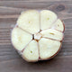 Top-down view of Premium Northern White garlic head cross-section showing large pale cloves on a wooden surface