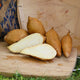 Front view of White Yam sweet potato tubers showing light tan skin and bright white flesh, halved on a wooden cutting board