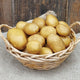 Basket of german butterball potatoes on a textured surface with a wooden background