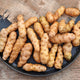 Top view of Ozette fingerling potatoes showing buff-colored skin and elongated shape on a black plate with burlap background