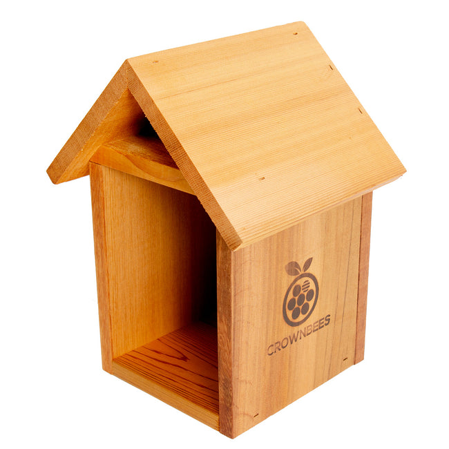 Three-quarter front view of cedar tower bee house showing open cavity for reed nesting and pitched roof on white background
