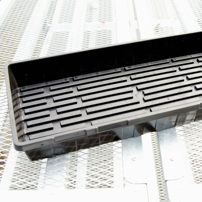 Angled view of black Sunpack MEGA Color I.D. tray showing interior ridges and drainage slots on a wooden surface