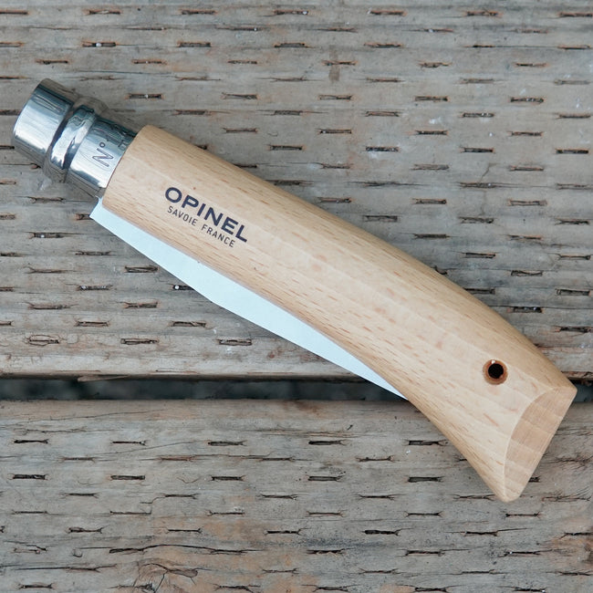 Folded Opinel No 12 saw with wooden handle and metal blade on a woven surface