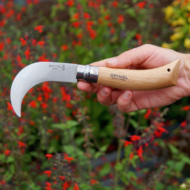 No 10 Opinel Billhook knife held in a hand with a garden background