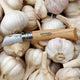 Opinel chestnut & garlic knife on a pile of garlic bulbs
