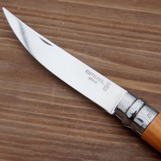 Close-up of Effilé No. 10 harvesting knife showing stainless-steel blade and Opinel logo on a wooden surface