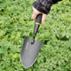 Angled top view of Handy Trowel tool showing pointed high-carbon steel blade and ergonomic handle on green foliage background