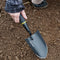 Angled view of Handy Trowel showcasing pointed high-carbon steel blade and ergonomic black handle resting in soil