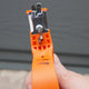 Front view of 6-in-1 multi sharpener showing orange handheld tool with four sharpening slots, hand guard, and non-slip grip