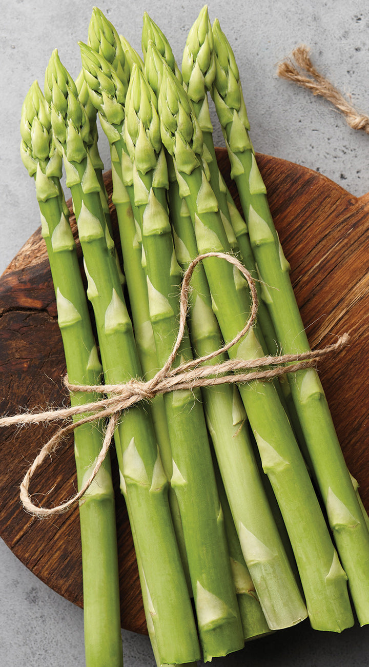 Bunch of green asparagus tied with twine on a wooden board