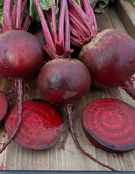 Beets with green tops on a wooden surface