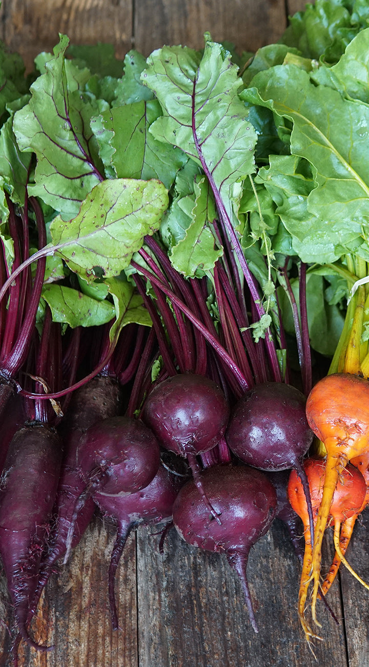 Beets with green leaves on a wooden surface