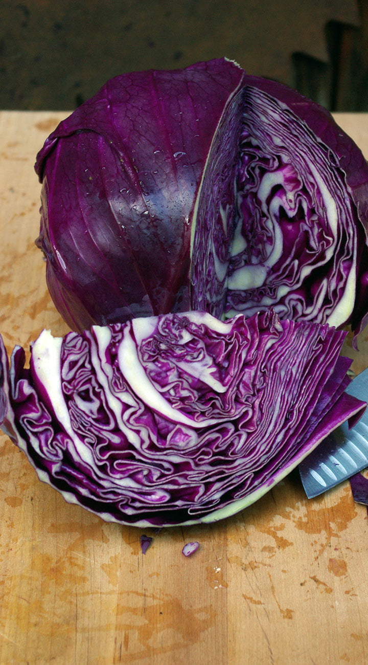 Halved purple cabbage on a wooden cutting board