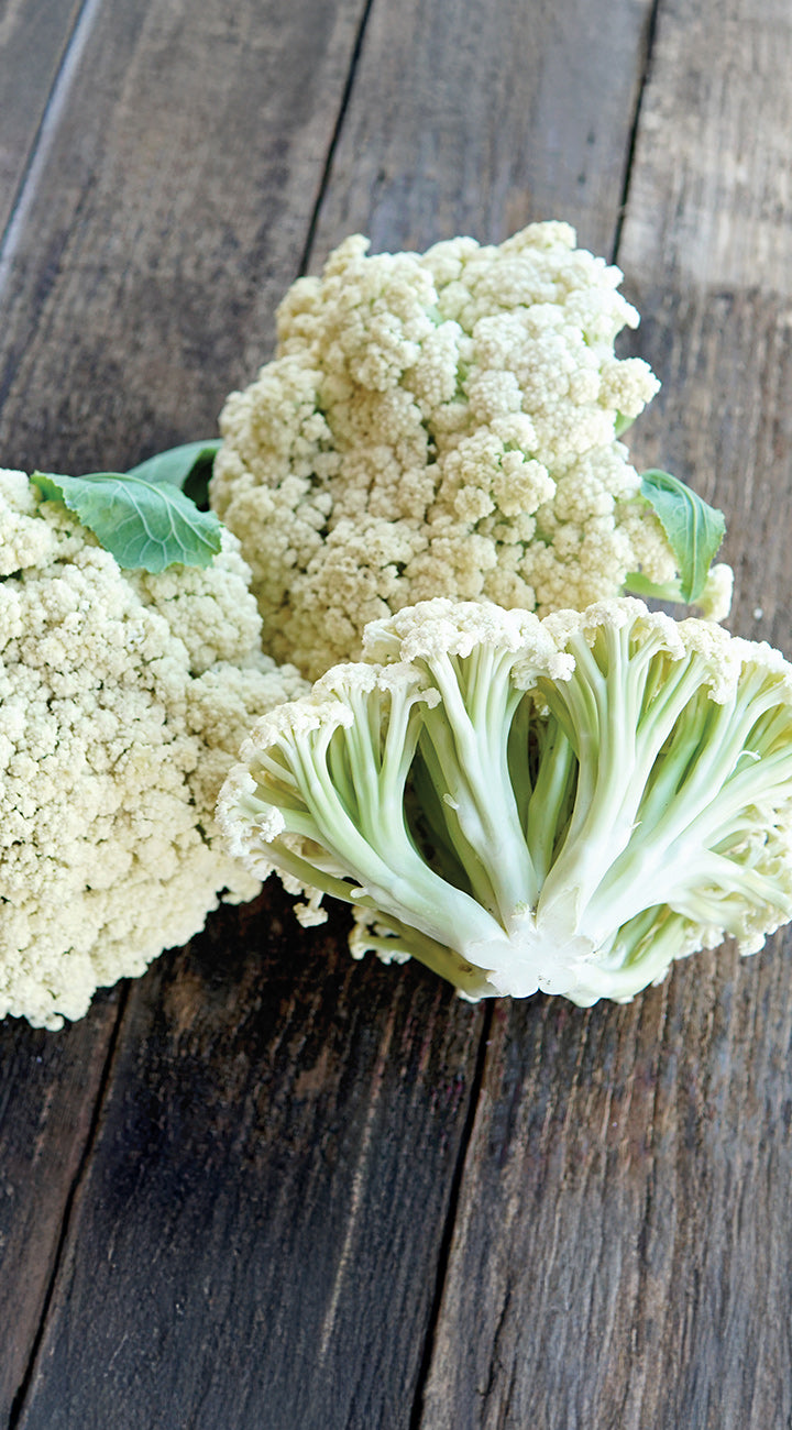 Three heads of cauliflower on a wooden surface