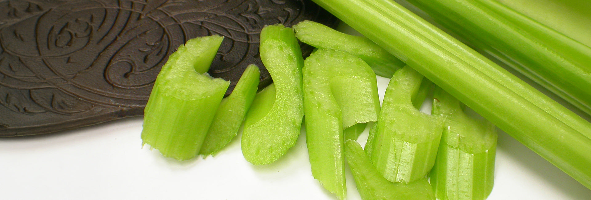 Sliced celery sticks on a white background with a close-up of a chocolate cookie.
