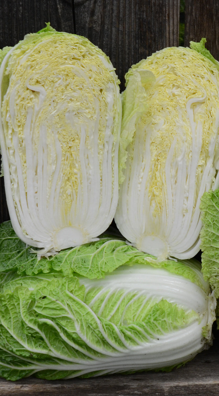 Three green chinese cabbages on a wooden surface