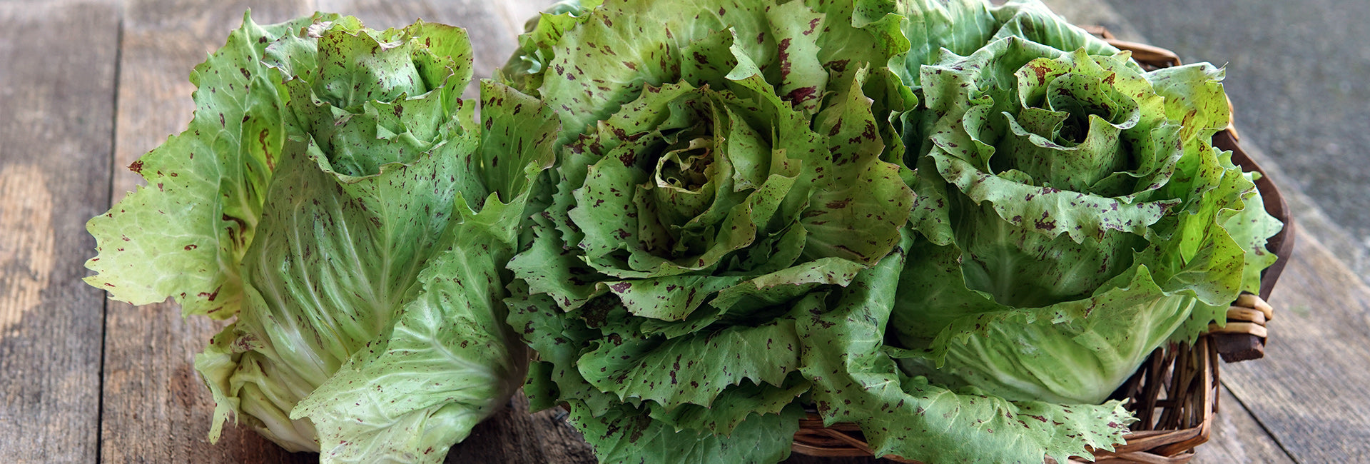 Basket of green leafy vegetables on a wooden surface
