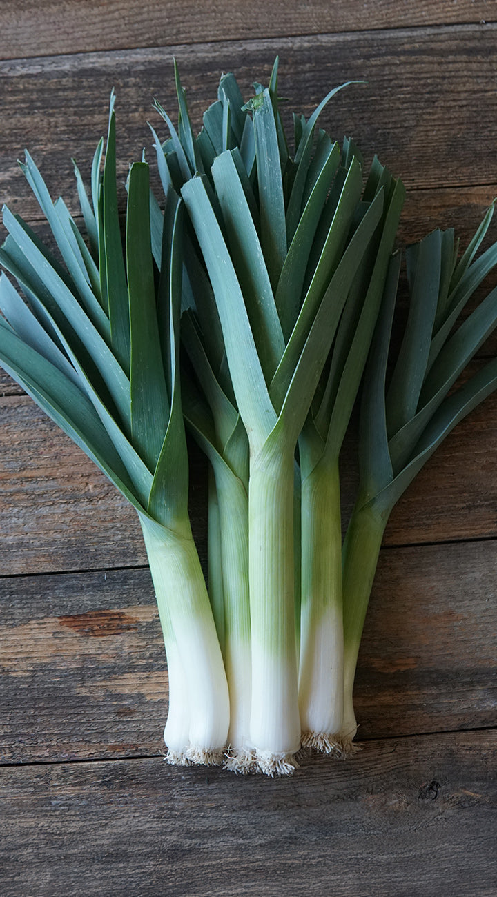 Bunch of green leeks on a wooden surface