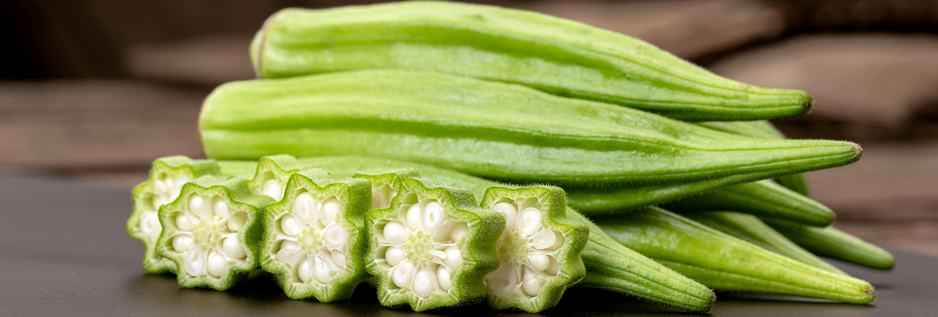 Green okra with a close-up of its interior on a brown background
