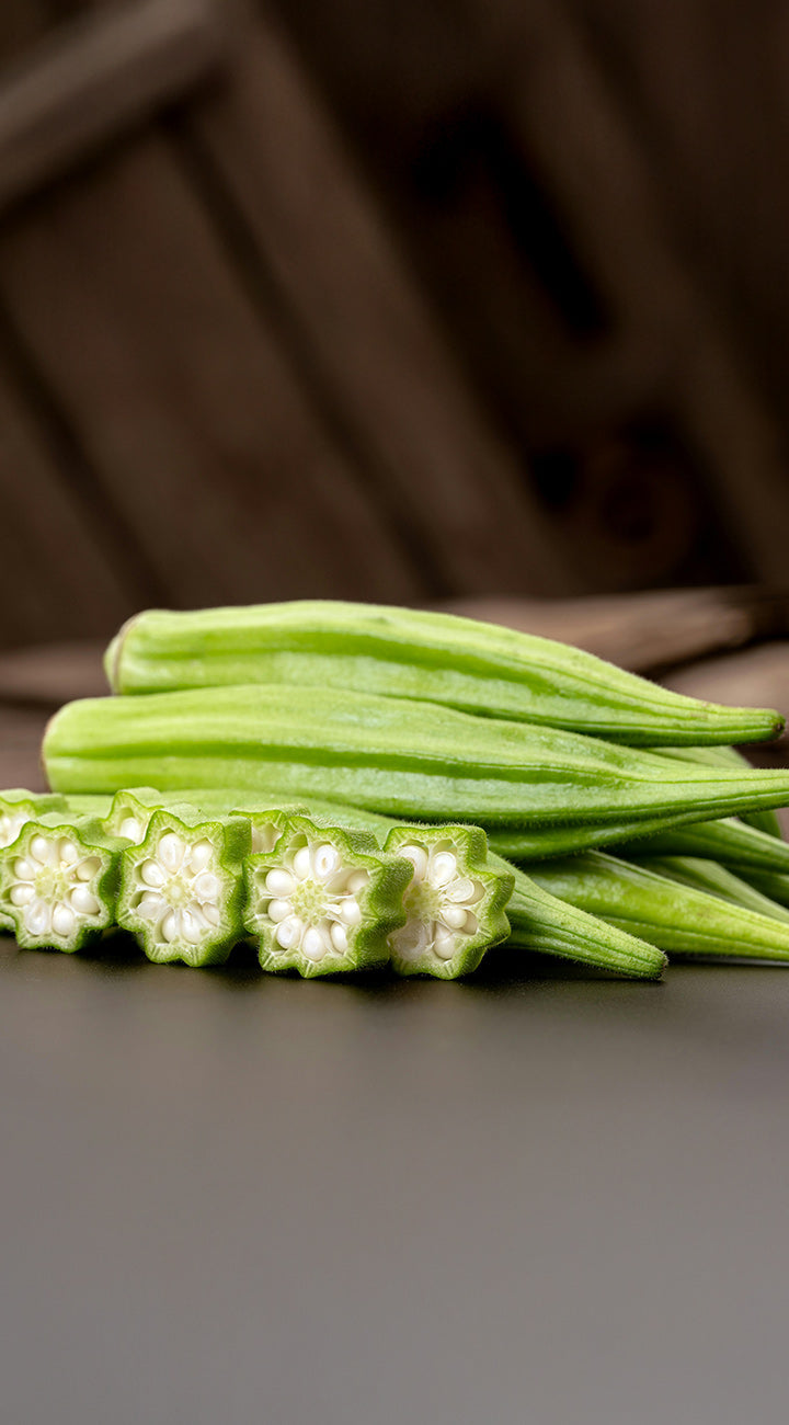 Green okra on a dark surface with a blurred background
