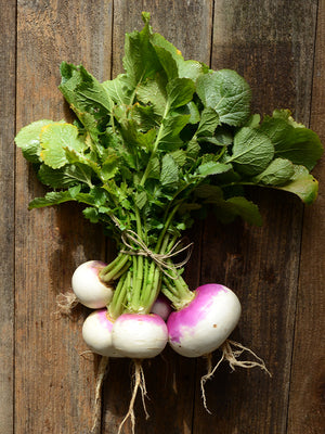Bunch of turnips with green leaves on a wooden background