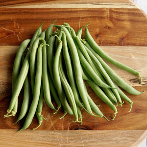 Overhead view of Desperado green beans showing medium-green straight snap pods on a wooden cutting board