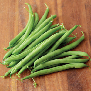 Top view of Antigua snap beans showing a pile of straight, slender green pods on a wooden cutting board