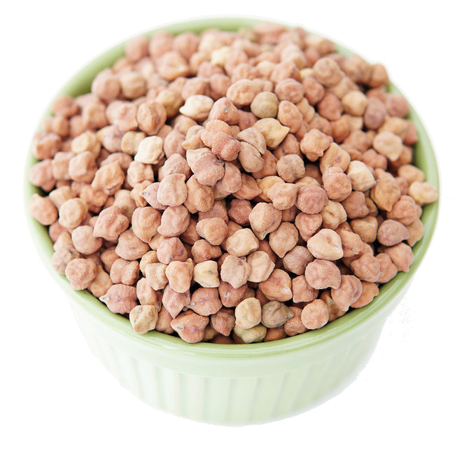 Top-down view of Myles garbanzo beans in a white bowl showing small light-brown desi chickpeas on a white background