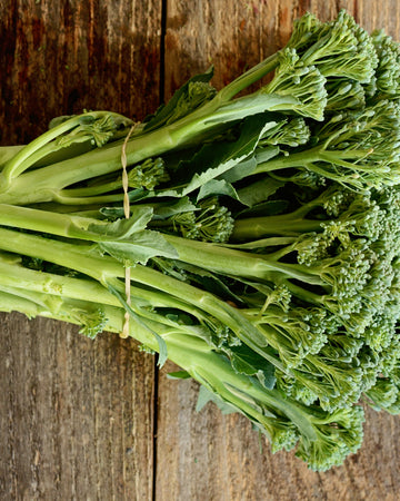 Close-up of Aspabroc broccolini stems showcasing elongated tender stems and small domed florets on a wooden surface