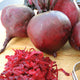 Close-up of Boro beet roots showing smooth dark-red skin and shredded beet on a wooden cutting board
