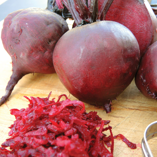 Close-up of Boro beet roots showing smooth dark-red skin and shredded beet on a wooden cutting board