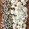 Top-down view of Glass Gem corn kernels showcasing multicolored jewel-tone kernels and popped white popcorn on a wooden board