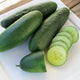 Close-up of Raider cucumbers showing uniform cylindrical glossy deep-green fruit with sliced cucumber on a white plate
