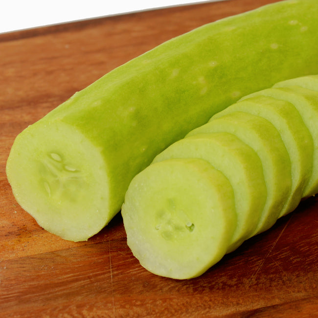Close-up of Lime Crisp cucumber sliced to show light green skin and pale, crisp interior on a wooden cutting board